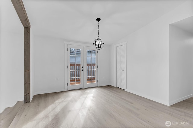 unfurnished dining area with baseboards, french doors, wood finished floors, and a notable chandelier