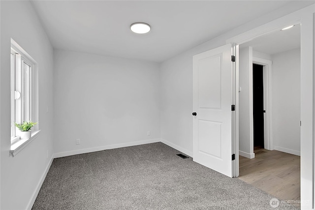 carpeted empty room featuring baseboards