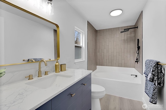 full bathroom featuring tiled shower / bath combo, vanity, toilet, and wood finished floors