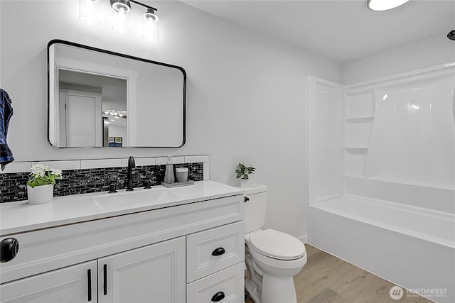 bathroom with shower / bathtub combination, toilet, wood finished floors, vanity, and decorative backsplash