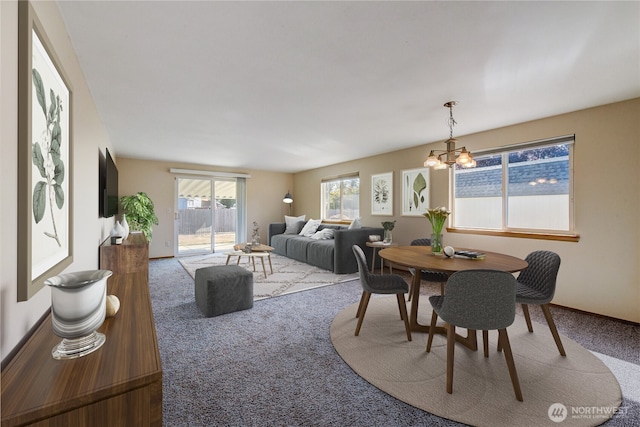 carpeted dining space with baseboards and a notable chandelier