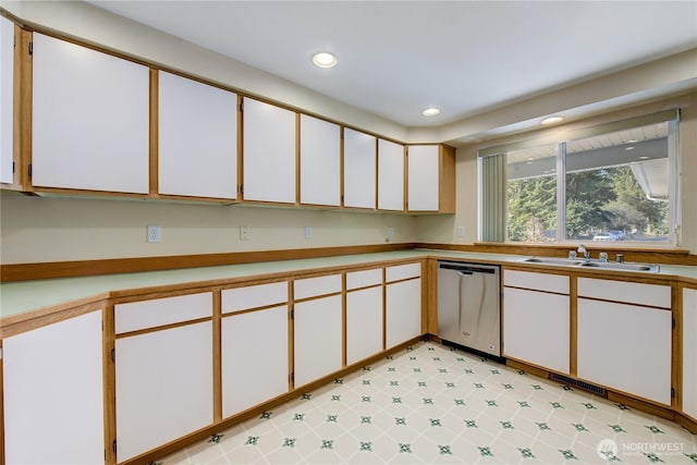 kitchen with stainless steel dishwasher, light countertops, recessed lighting, and a sink