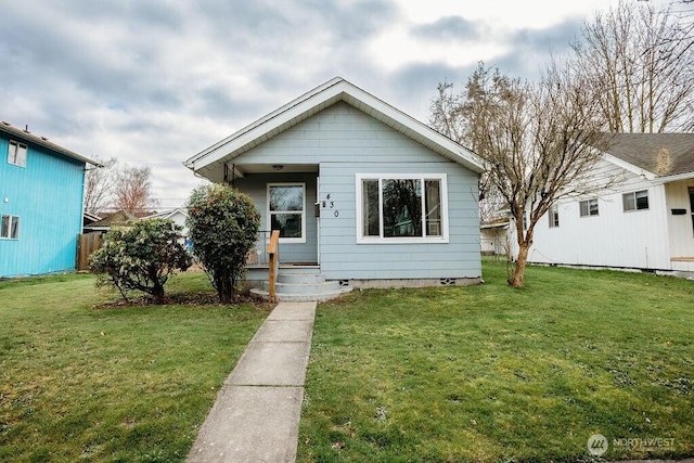 bungalow featuring covered porch and a front yard