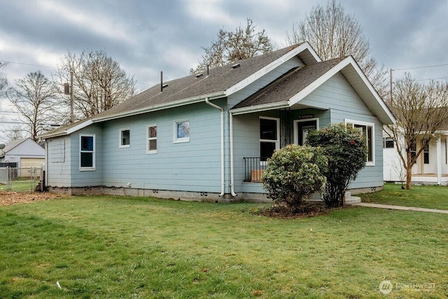 exterior space featuring a shingled roof, fence, and a lawn