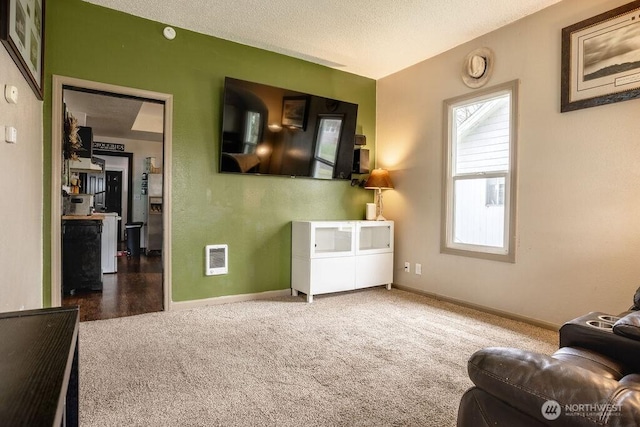 carpeted living area featuring visible vents, a textured ceiling, and baseboards