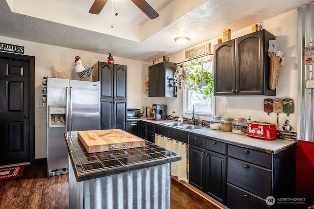 kitchen with a textured ceiling, dark wood-type flooring, a sink, a ceiling fan, and stainless steel refrigerator with ice dispenser