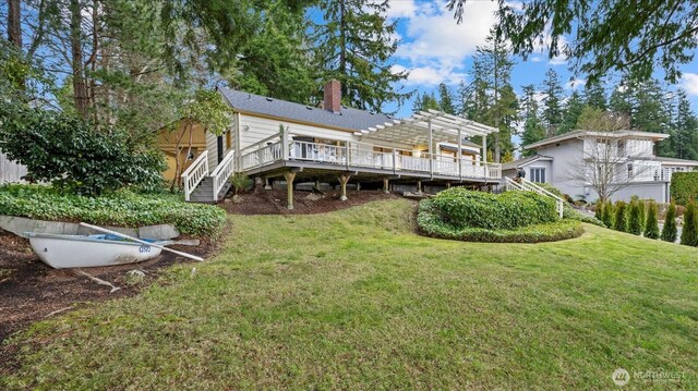 back of property featuring a wooden deck, a pergola, a chimney, stairs, and a lawn