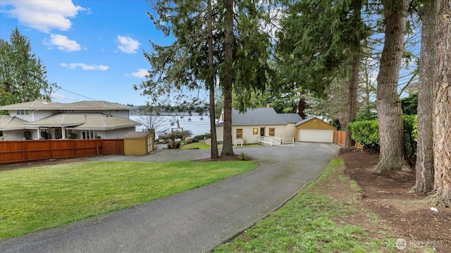 ranch-style house with a front lawn, fence, aphalt driveway, a garage, and an outdoor structure