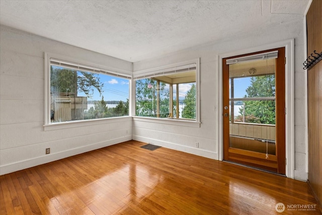 unfurnished room featuring visible vents, a textured ceiling, baseboards, and wood-type flooring