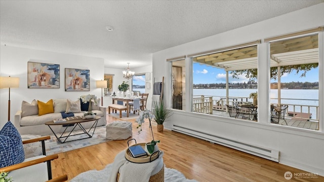 living area with a notable chandelier, baseboard heating, a water view, and wood finished floors