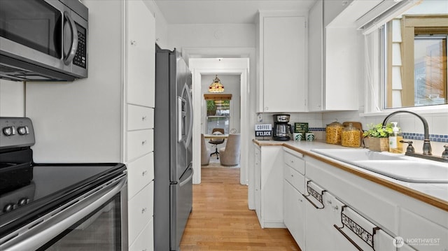 kitchen with a sink, light countertops, white cabinets, and stainless steel appliances