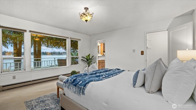 carpeted bedroom with a water view, baseboard heating, ensuite bathroom, and a textured ceiling