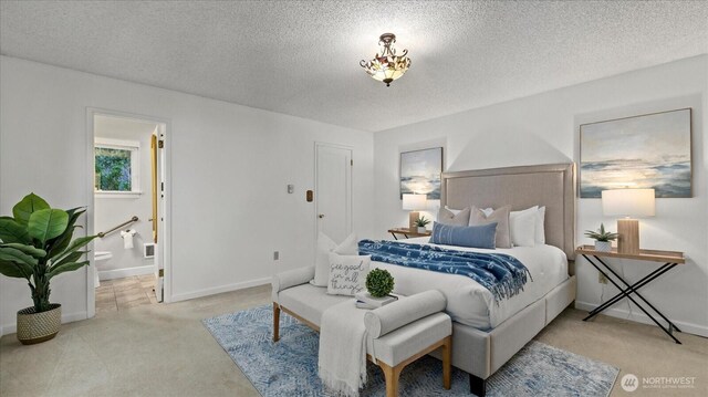 carpeted bedroom featuring a textured ceiling, ensuite bathroom, and baseboards