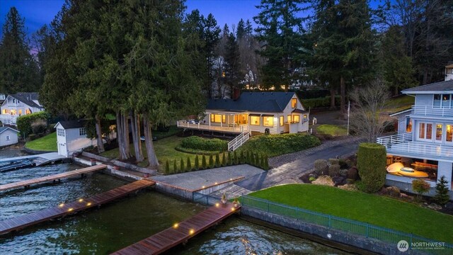 rear view of house with an outdoor structure, a lawn, and a water view