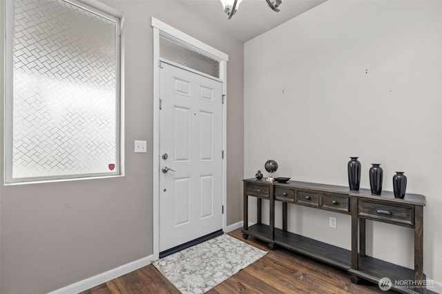 foyer entrance featuring dark wood finished floors, a notable chandelier, and baseboards