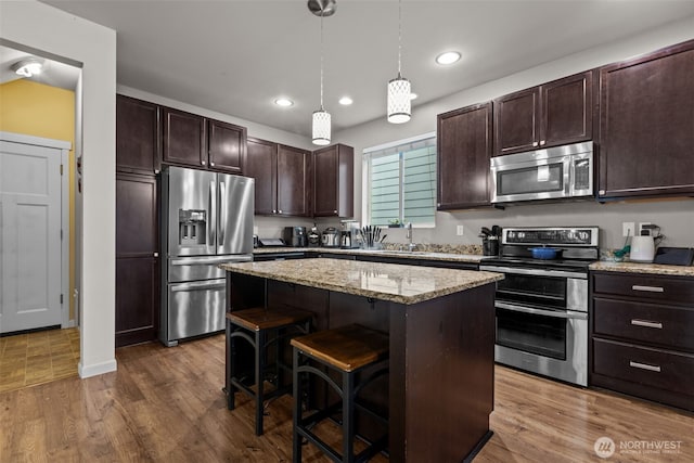 kitchen featuring dark brown cabinetry, a center island, stainless steel appliances, and dark wood-type flooring