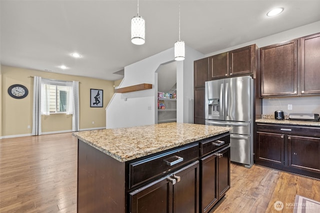 kitchen with light stone counters, dark brown cabinets, light wood-style flooring, and stainless steel fridge with ice dispenser