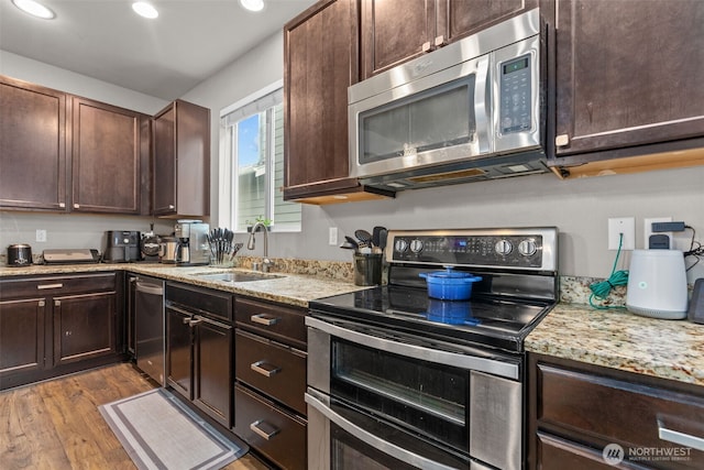 kitchen with a sink, dark brown cabinetry, appliances with stainless steel finishes, and wood finished floors