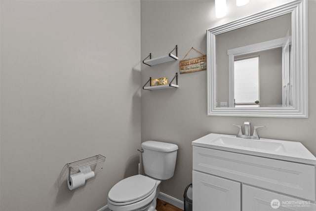 bathroom with vanity, toilet, and baseboards