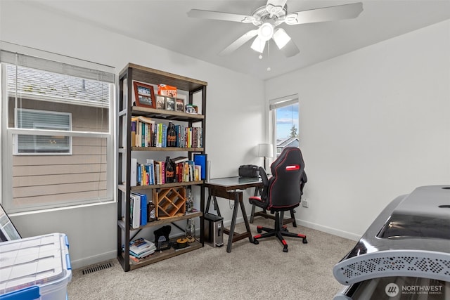 carpeted home office featuring visible vents, baseboards, and ceiling fan