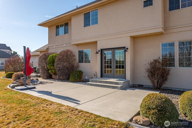 rear view of property featuring french doors, a patio area, and stucco siding