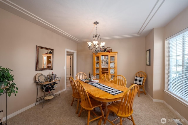 dining space with a notable chandelier, light colored carpet, and baseboards