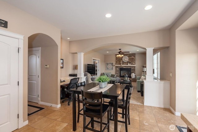 dining space with recessed lighting, a fireplace, baseboards, ceiling fan, and ornate columns