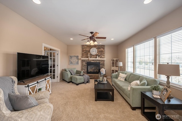 living room with recessed lighting, a stone fireplace, light colored carpet, and a ceiling fan