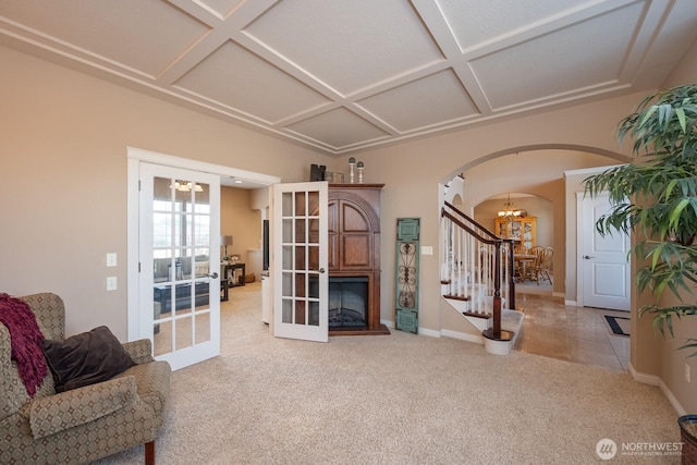 sitting room with arched walkways, carpet, a chandelier, and coffered ceiling