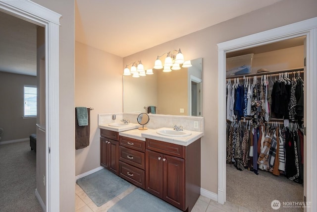 bathroom featuring double vanity, tile patterned floors, a walk in closet, and a sink