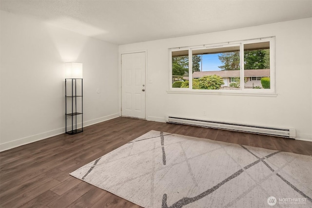 spare room with a baseboard radiator, baseboards, and wood finished floors