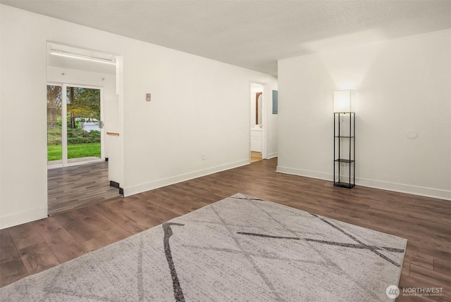 unfurnished room featuring a textured ceiling, baseboards, and wood finished floors