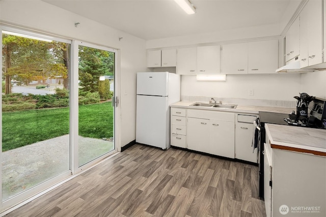 kitchen with light countertops, black electric range oven, freestanding refrigerator, white cabinets, and under cabinet range hood