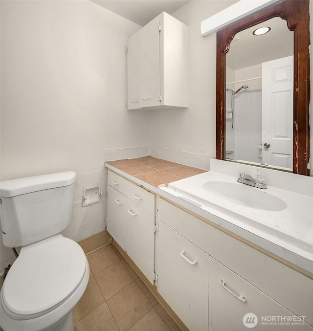 bathroom featuring toilet, walk in shower, tile patterned flooring, and vanity