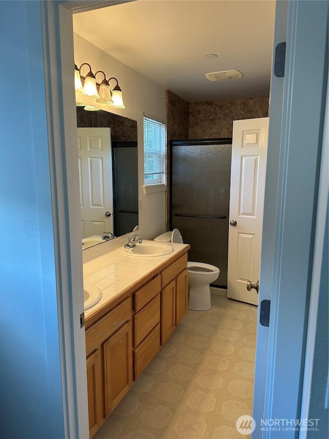 full bathroom with a sink, a shower stall, toilet, and double vanity