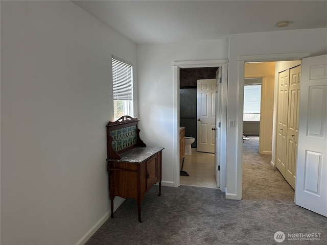 hallway with carpet floors and baseboards