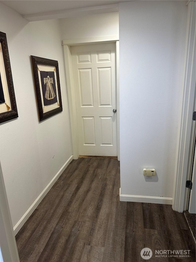 corridor with baseboards and dark wood-type flooring