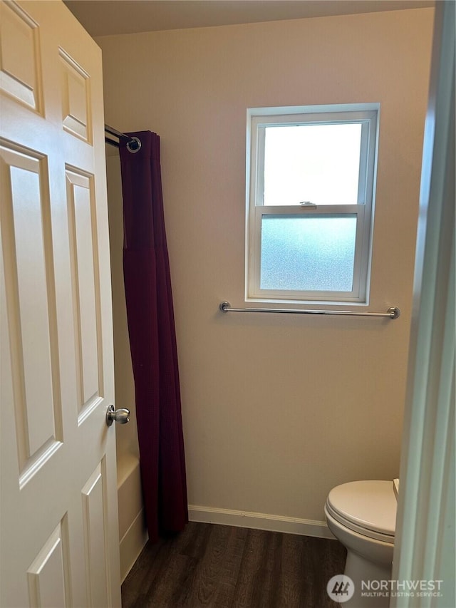 bathroom with shower / bath combo with shower curtain, wood finished floors, toilet, and baseboards