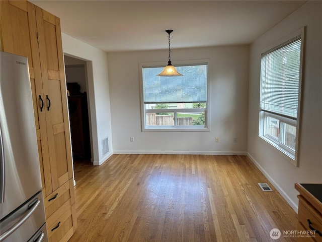 unfurnished dining area featuring light wood finished floors, visible vents, and a wealth of natural light