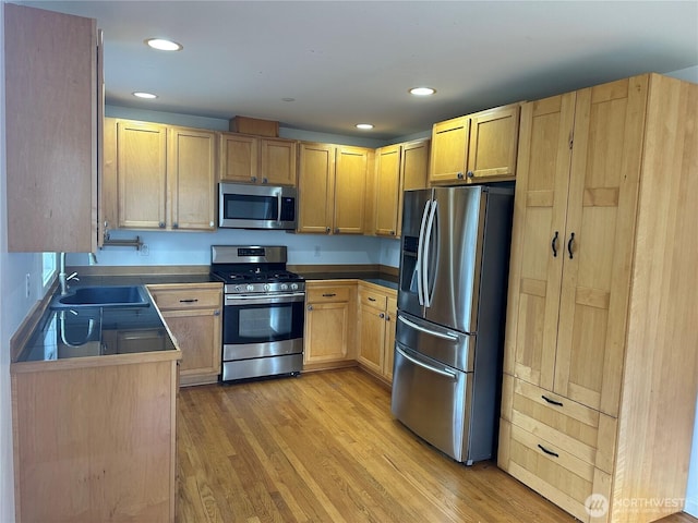 kitchen featuring appliances with stainless steel finishes, light brown cabinetry, light wood-type flooring, a sink, and recessed lighting