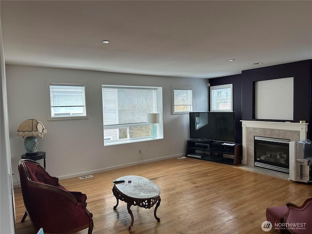 living room featuring a wealth of natural light, visible vents, baseboards, and wood finished floors