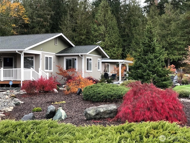 view of front facade with a shingled roof and a porch