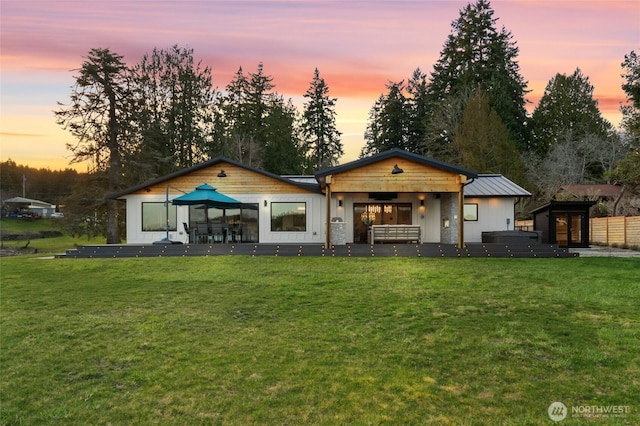 back of house featuring a standing seam roof, metal roof, and a yard