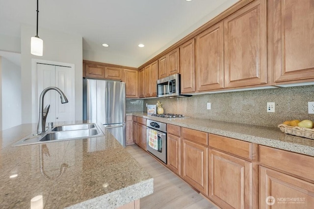 kitchen with light stone counters, backsplash, stainless steel appliances, and a sink