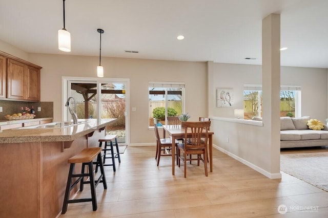 dining space with light wood finished floors, plenty of natural light, and baseboards