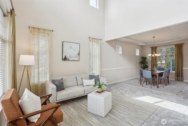 carpeted living area with a chandelier and baseboards