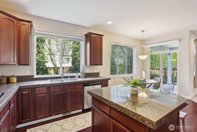kitchen with stainless steel dishwasher, a sink, decorative light fixtures, wood finished floors, and recessed lighting