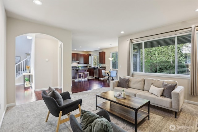 living area with arched walkways, recessed lighting, dark wood-style floors, stairway, and baseboards