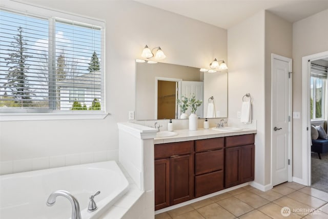 bathroom with tile patterned floors, a garden tub, double vanity, and baseboards