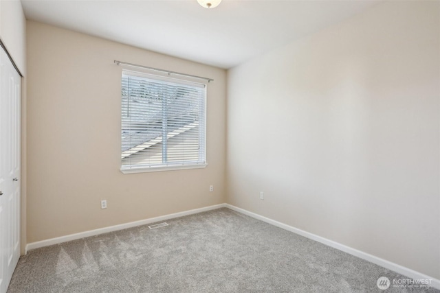 carpeted spare room featuring baseboards